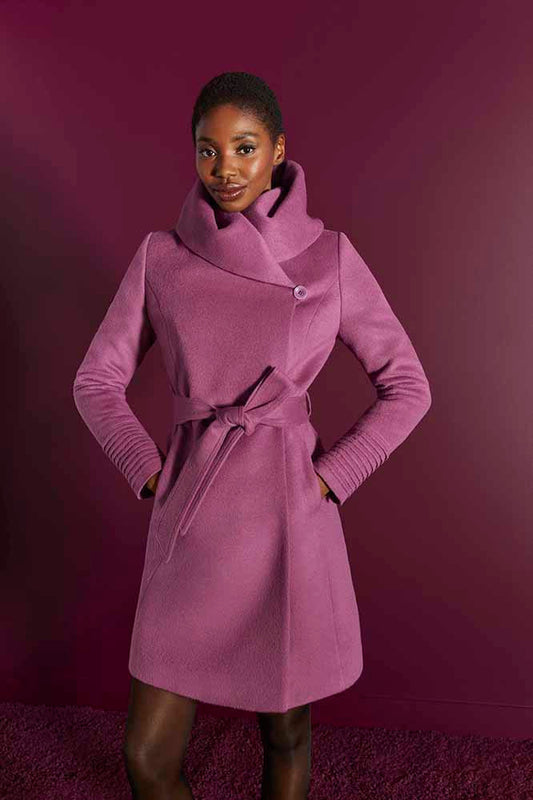Front cropped view of model wearing a Sentaler mid length mauve pink coat made of baby alpaca wool, with a hooded collar, worn belted.