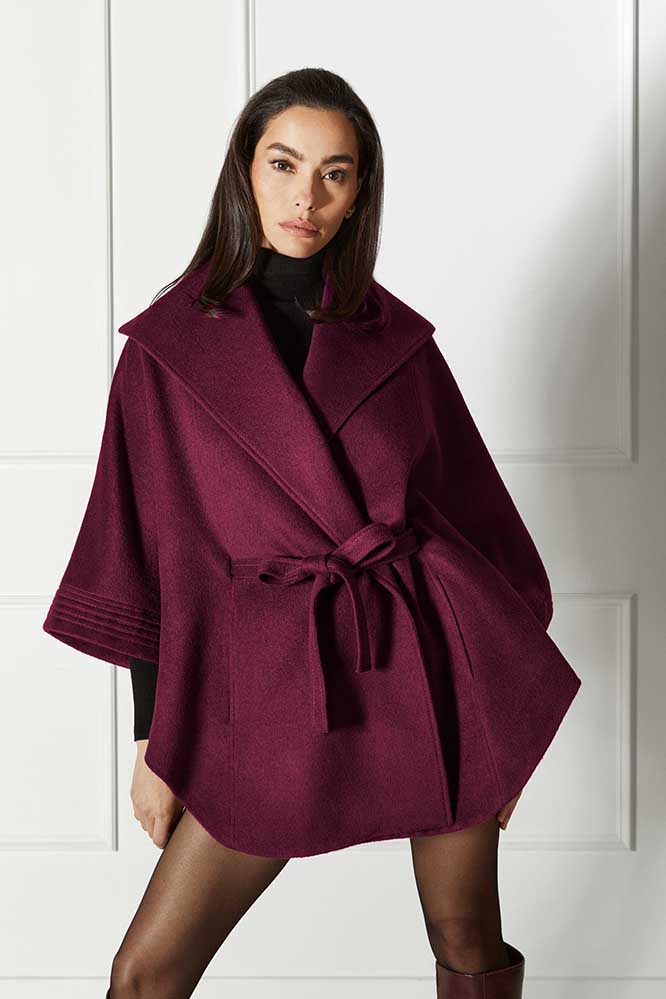 Front view of model wearing a Sentaler cherry lacquer cape made of baby alpaca wool, with a shawl collar, worn belted.