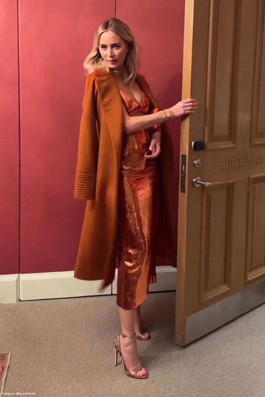 British actress Emily Blunt is wearing the SENTALER Suri Alpaca Long Notched Collar Raglan Sleeve Wrap Coat in Burnt Orange while leaving her dressing room.