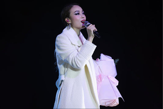 Hong Kong singer and Cantopop diva Joey Yung is wearing the SENTALER Bouclé Alpaca Long Notched Collar Wrap Coat in Ivory White on stage performing.