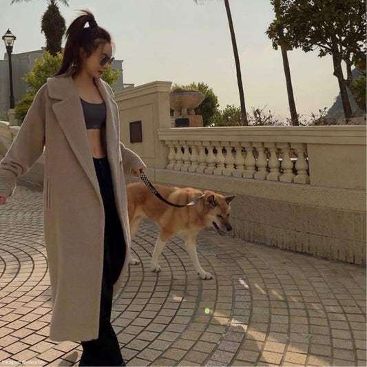 Hong Kong actress Rosina Lam is wearing the SENTALER Bouclé Alpaca Long Oversized Notched Collar Coat in Sand Beige while posing and walking her dog.