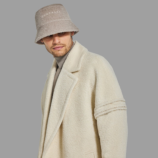 Image features the Forbes logo and an image of a male model wearing the Sentaler Mens Bouclé Alpaca Bucket Hat featured in Bouclé Alpaca and available in Sand Neutral. Seen close up from front.