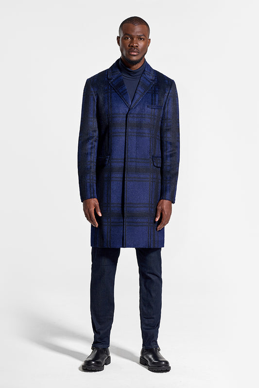 Image features the Forbes logo and an image of a male model wearing the Sentaler Technical Suri Alpaca Notched Lapel Overcoat featured in Technical Suri Alpaca and available in Navy Plaid Blue. Seen from front above the knees.