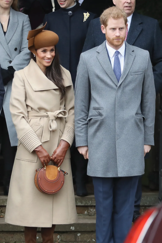 Image features the Vogue logo and an image of the Duchess of Cambridge, Meghan Markle wearing the Sentaler Long Wide Collar Wrap Coat featured in Baby Alpaca and available in Camel alongside Prince Harry.