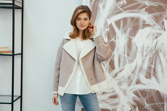 Image features the WWD logo and an image of a female model wearing the Sentaler Bouclé Alpaca Dropped Shoulder Boyfriend Jacket featured in Bouclé Alpaca and available in Sand Neutral. Seen from front above the knees open.