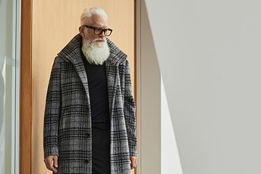 Image features the WWD logo and an image of a male model wearing the Sentaler Technical Suri Alpaca Double Collar Overcoat featured in Technical Bouclé Suri Alpaca and available in Grey Plaid Grey. Seen from front open.