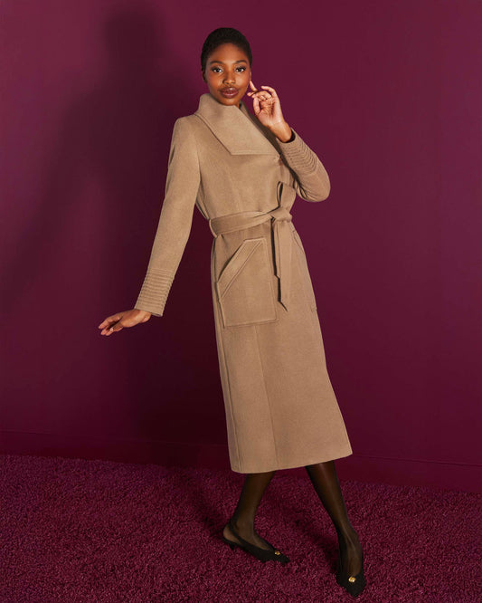 Front view of model wearing a Sentaler camel long wrap coat made of baby alpaca wool, with a wide collar, worn belted.