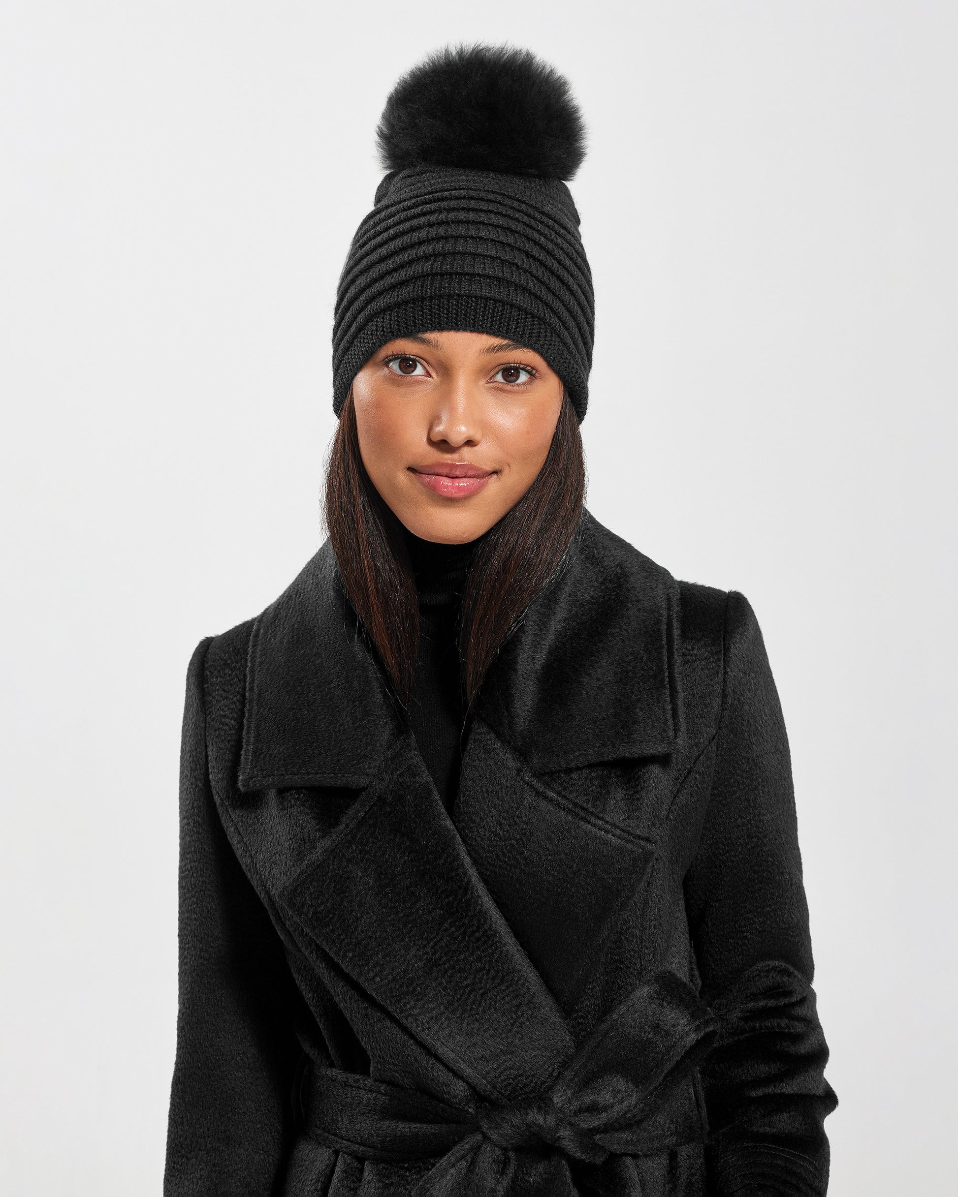 Front view of model wearing Sentaler's signature black ribbed hat, paired with a matching black coat.