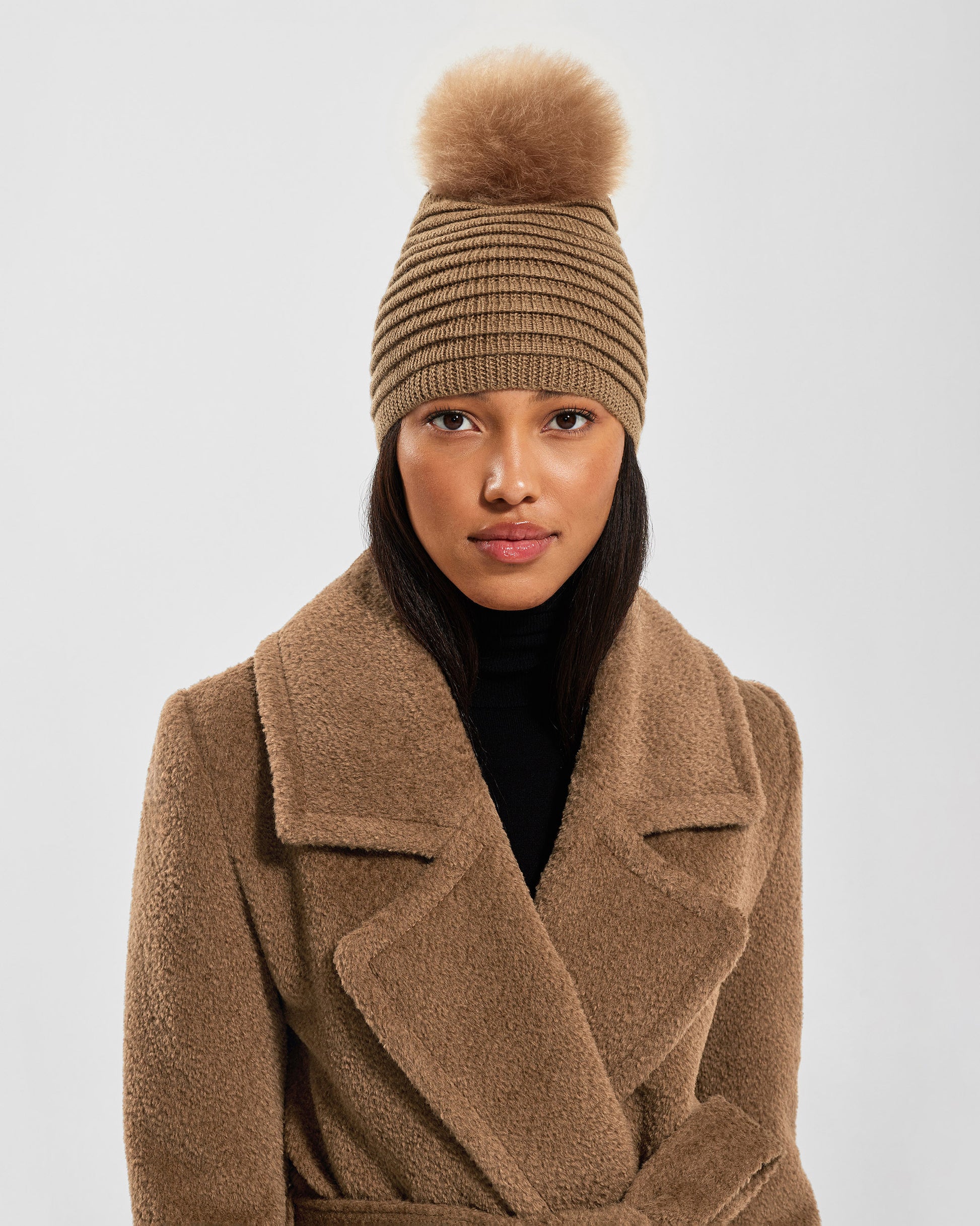 Front view of model wearing Sentaler's signature dark camel ribbed hat, scarf, and gloves, paired with a matching dark camel coat.