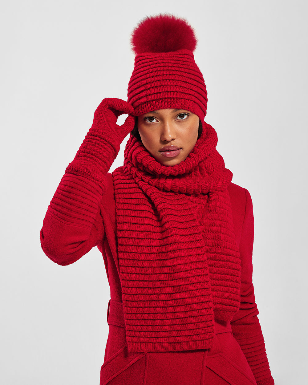 Front view of model wearing Sentaler's signature red ribbed hat, scarf, and gloves, paired with a matching scarlet red coat.