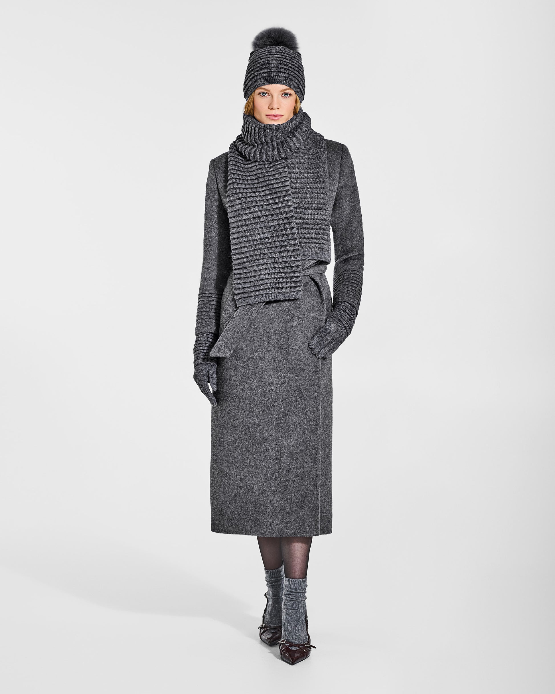 Front view of model wearing Sentaler's signature grey mélange ribbed hat, scarf, and gloves, paired with a matching grey mélange coat.