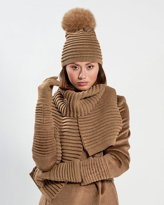 Sentaler Adult Ribbed Dark Camel Gloves, Adult Ribbed Dark Camel Hat With Fur Pompon, and Adult Ribbed Dark Camel Scarf in Baby Alpaca yarn. Seen from front close up on female model.