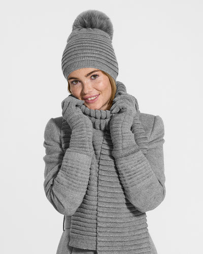 Sentaler Adult Ribbed Grey Gloves, Adult Ribbed Grey Hat With Fur Pompon, and Adult Ribbed Grey Scarf in Baby Alpaca yarn. Seen from front close up on female model.