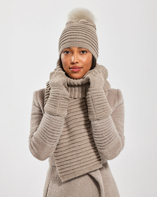 Front view of model wearing Sentaler's adult light taupe ribbed gloves, made of baby alpaca yarn, paired with a light taupe coat.