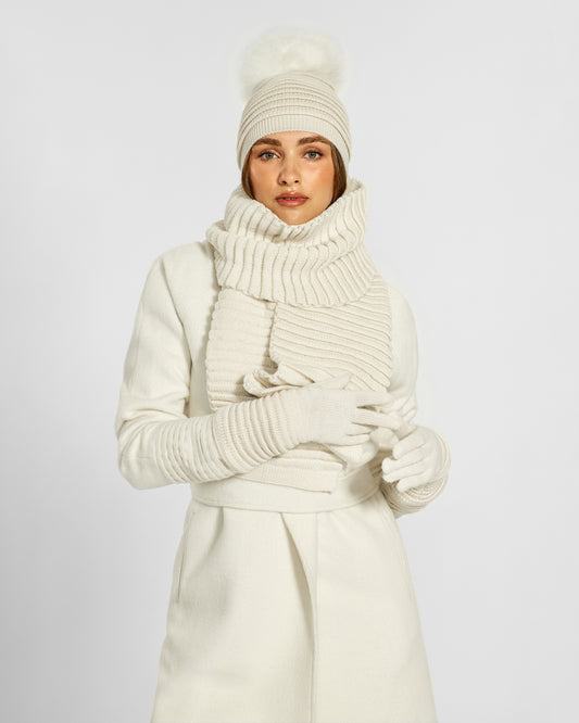 Front view of model wearing Sentaler's adult ivory ribbed gloves, made of baby alpaca yarn, paired with an ivory coat.