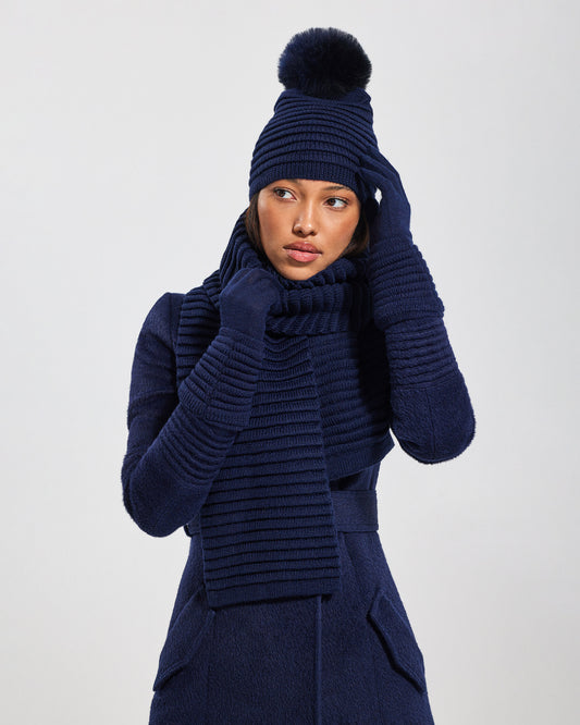 Front view of model wearing Sentaler's adult navy ribbed gloves, made of baby alpaca yarn, paired with a deep navy coat.