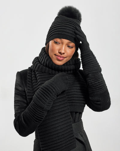 Sentaler Adult Ribbed Black Hat With Fur Pompon, Adult Ribbed Black Scarf, and Adult Ribbed Black Gloves in Baby Alpaca yarn. Seen from front close up on female model.