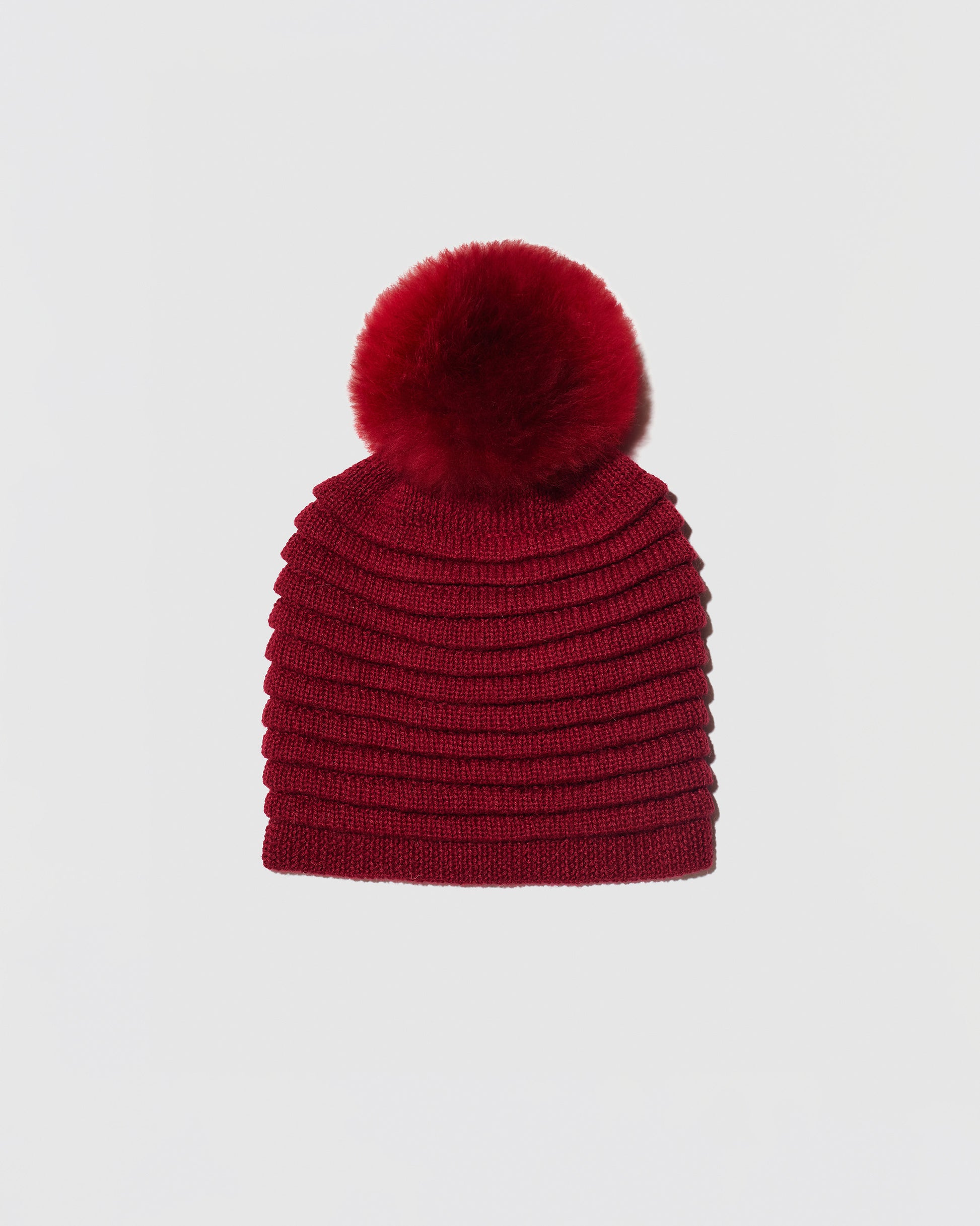 Sentaler women’s garnet red ribbed winter hat made of Baby Alpaca fabric with oversized fur pompom, displayed on a white background.