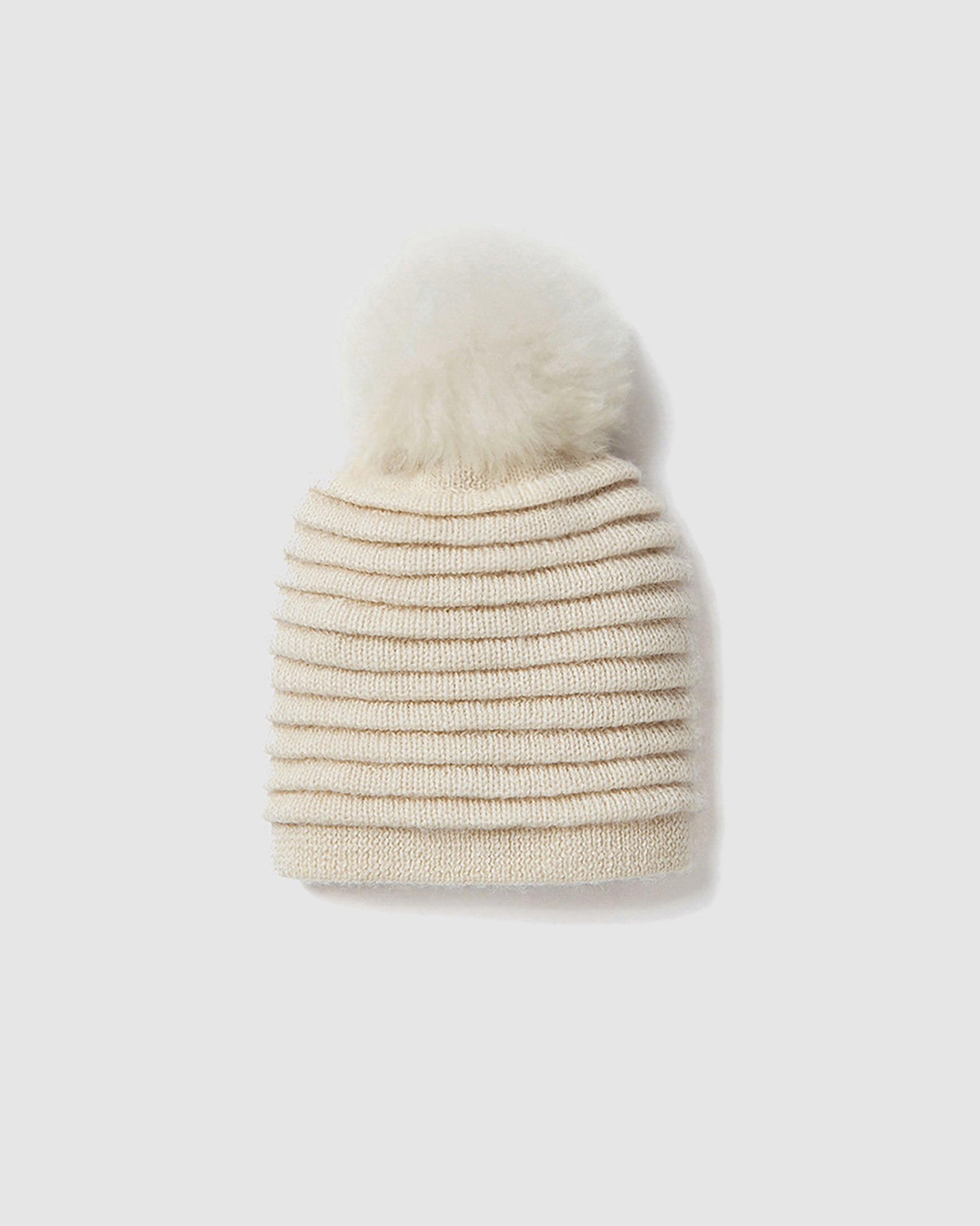 Sentaler women’s ivory ribbed winter hat made of Baby Alpaca fabric with oversized fur pompom, displayed on a white background.