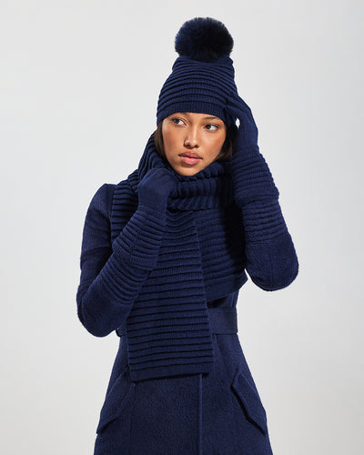 Sentaler Adult Ribbed Navy Hat With Fur Pompon, Adult Ribbed Navy Scarf, and Adult Ribbed Navy Gloves in Baby Alpaca yarn. Seen from front close up on female model.