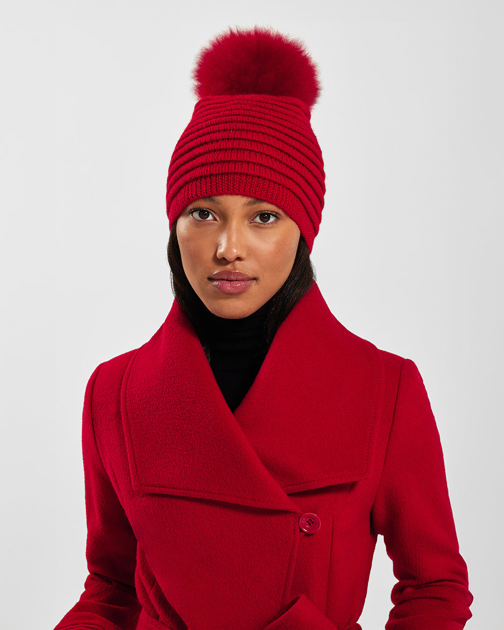 Sentaler Adult Ribbed Red Hat With Fur Pompon in Baby Alpaca yarn. Seen from front close up on female model.