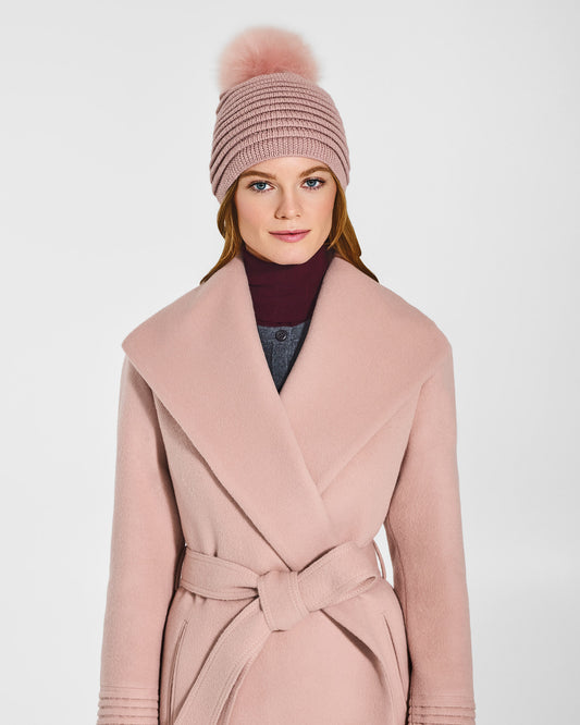 Front view of model wearing Sentaler's adult blush pink ribbed hat with fur pompon, made of baby alpaca yarn paired with a blush pink coat.