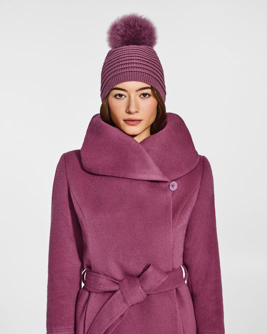 Front view of model wearing Sentaler's adult mauve pink ribbed hat with fur pompon, made of baby alpaca yarn, paired with a mauve pink coat.
