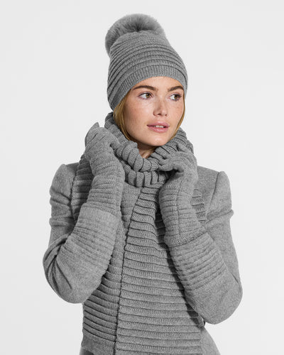 Sentaler Adult Ribbed Grey Scarf, Adult Ribbed Grey Hat With Fur Pompon, and Adult Ribbed Grey Gloves in Baby Alpaca yarn. Seen from front close up on female model.