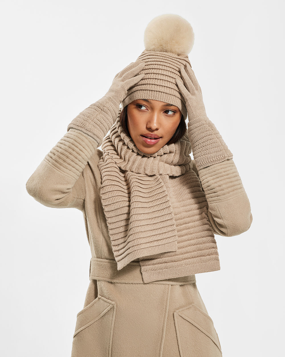 Sentaler Adult Ribbed Camel Scarf, Adult Ribbed Camel Hat With Fur Pompon, and Adult Ribbed Camel Gloves in Baby Alpaca yarn. Seen from front close up on female model.