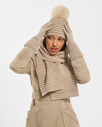 Sentaler Adult Ribbed Camel Scarf, Adult Ribbed Camel Hat With Fur Pompon, and Adult Ribbed Camel Gloves in Baby Alpaca yarn. Seen from front close up on female model.