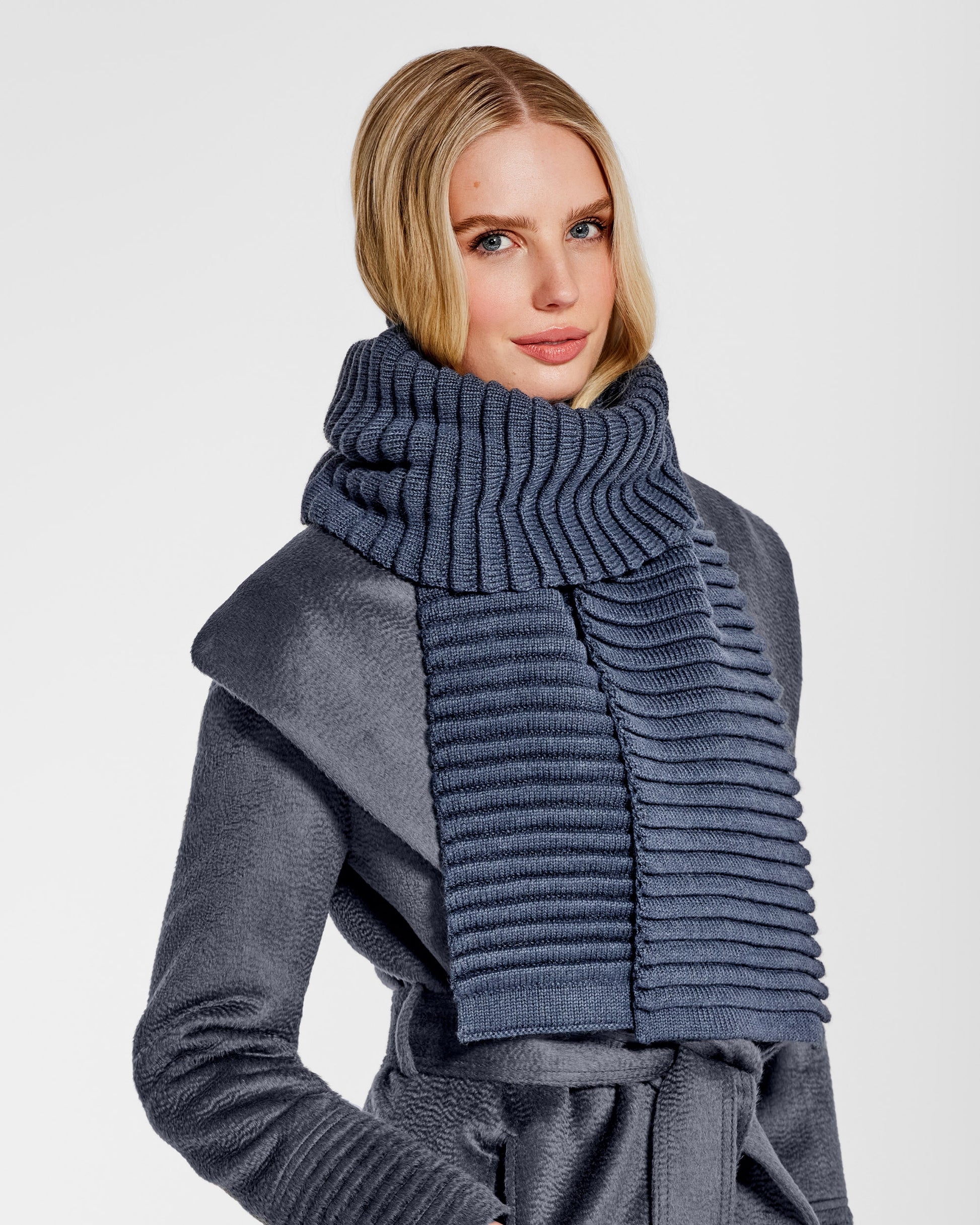 Side view of model wearing Sentaler's adult graphite ribbed scarf, made of baby alpaca yarn, paired with a graphite coat.
