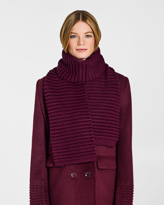 Front view of model wearing Sentaler's adult cherry lacquer ribbed scarf, made of baby alpaca yarn, paired with a cherry lacquer coat.