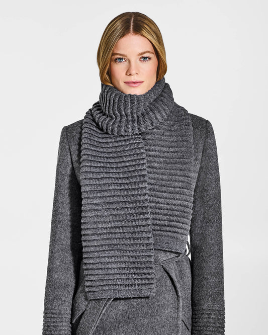Front view of model wearing Sentaler's adult grey mélange ribbed scarf, made of baby alpaca yarn, paired with a grey mélange coat.