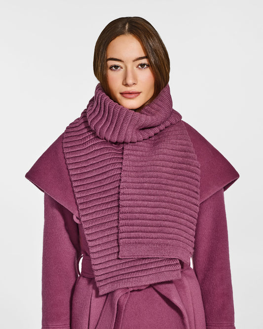 Front view of model wearing Sentaler's adult mauve pink ribbed scarf, made of baby alpaca yarn, paired with a mauve pink coat.