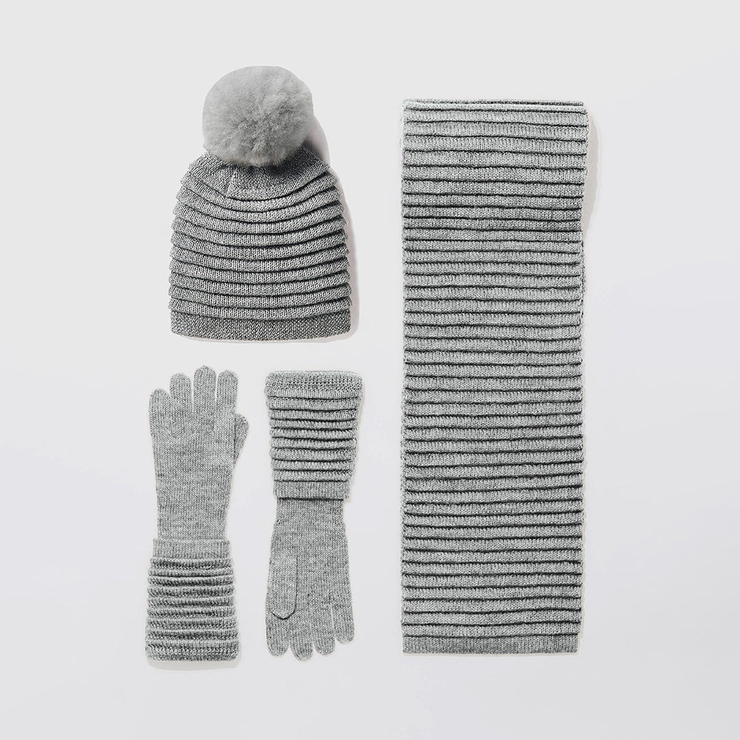 Sentaler Adult Ribbed Grey Hat with Oversized Fur Pompon, Ribbed Grey Scarf and Ribbed Grey Gloves flat lay.