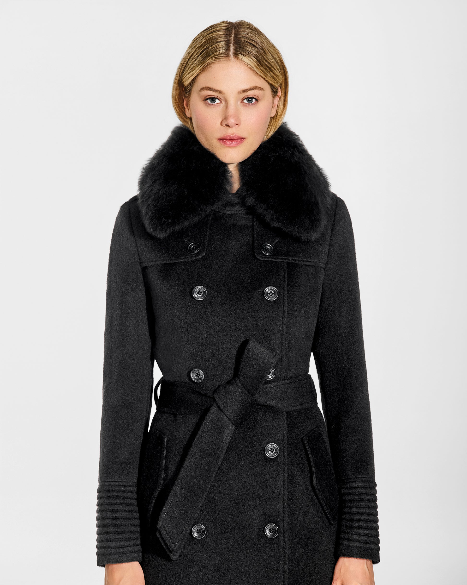 Front view close up of model wearing Sentaler's black alpaca shearling spread collar, paired with a black coat.