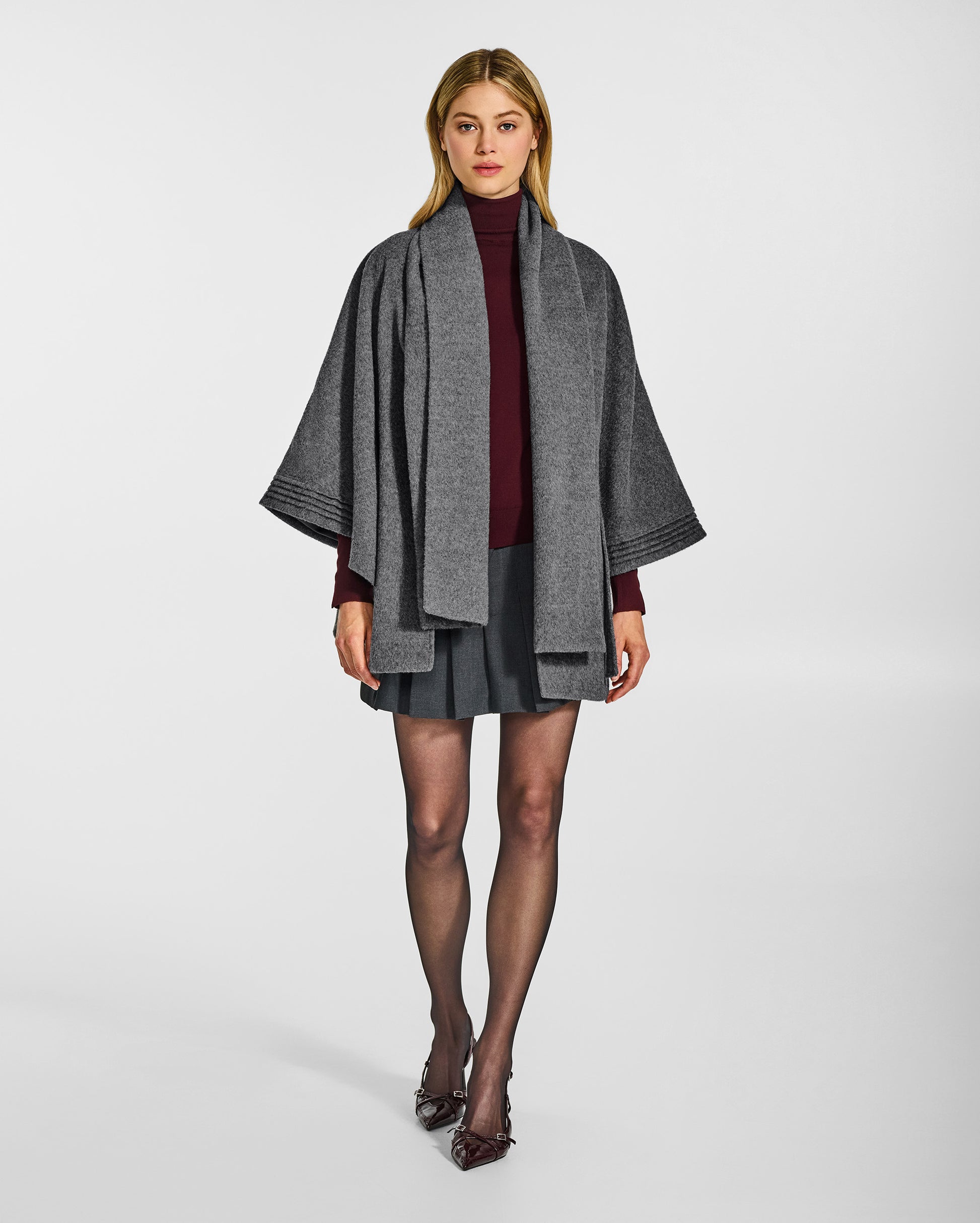Front view of model wearing a Sentaler grey mélange cape made of baby alpaca wool, with a scarf collar, worn open.