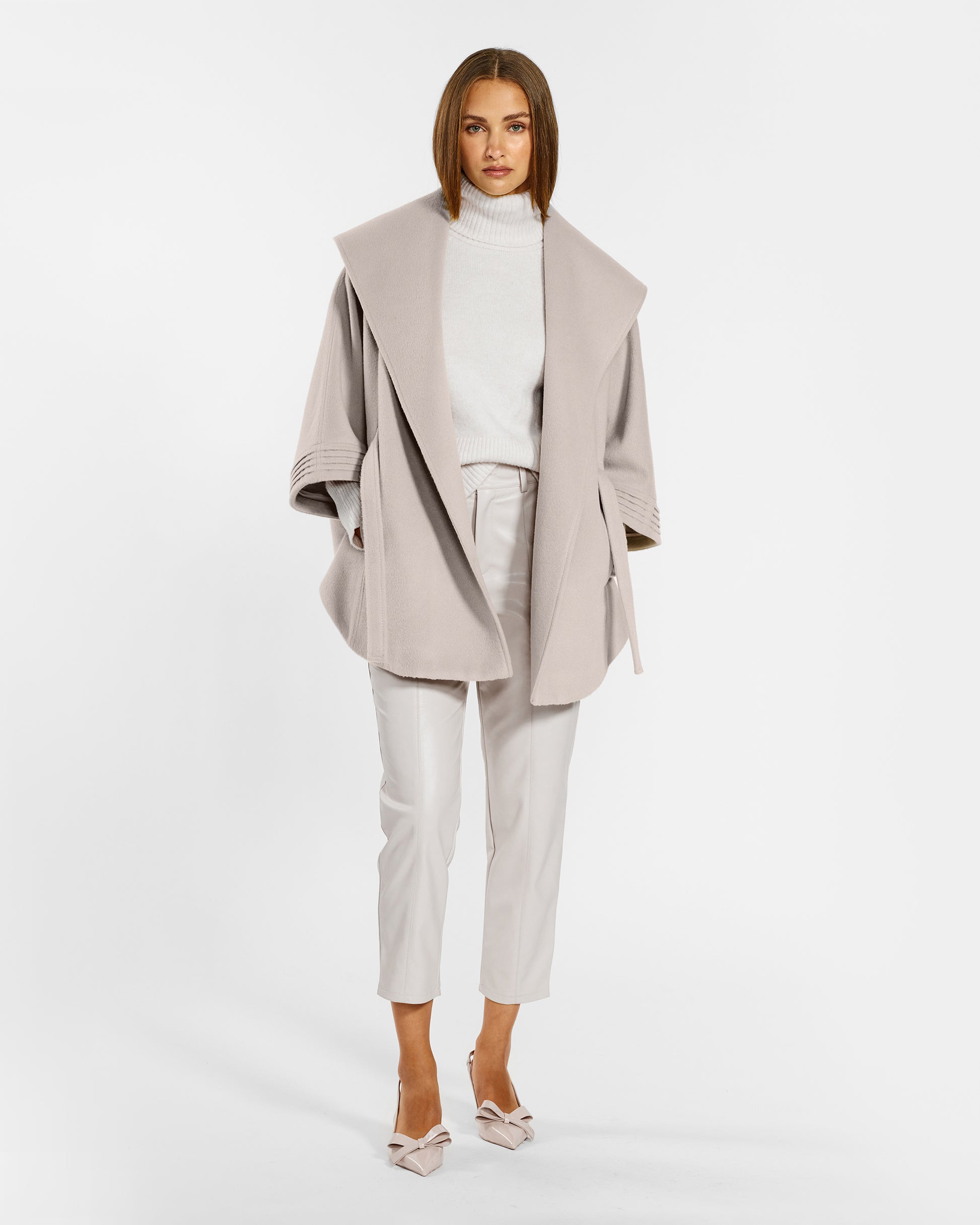 Front view of model wearing a Sentaler bleeker beige cape made of baby alpaca wool, with a shawl collar, worn open.