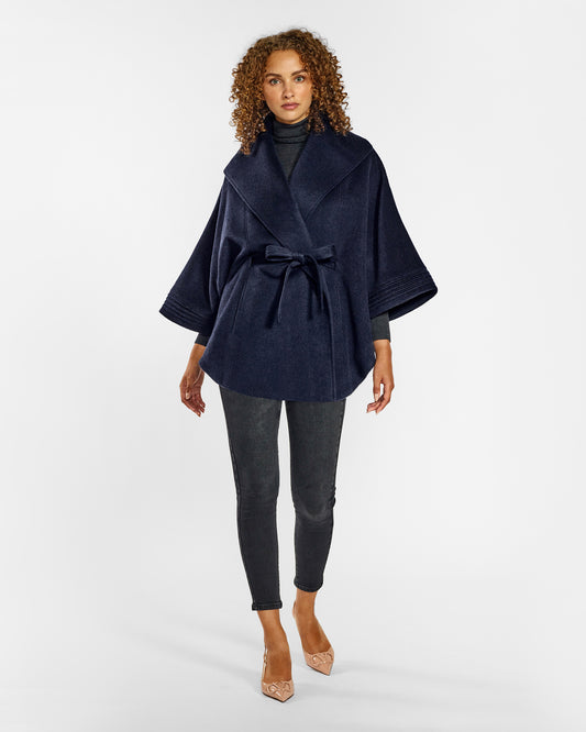 Front view of model wearing a Sentaler deep navy cape made of baby alpaca wool, with a shawl collar, worn belted.