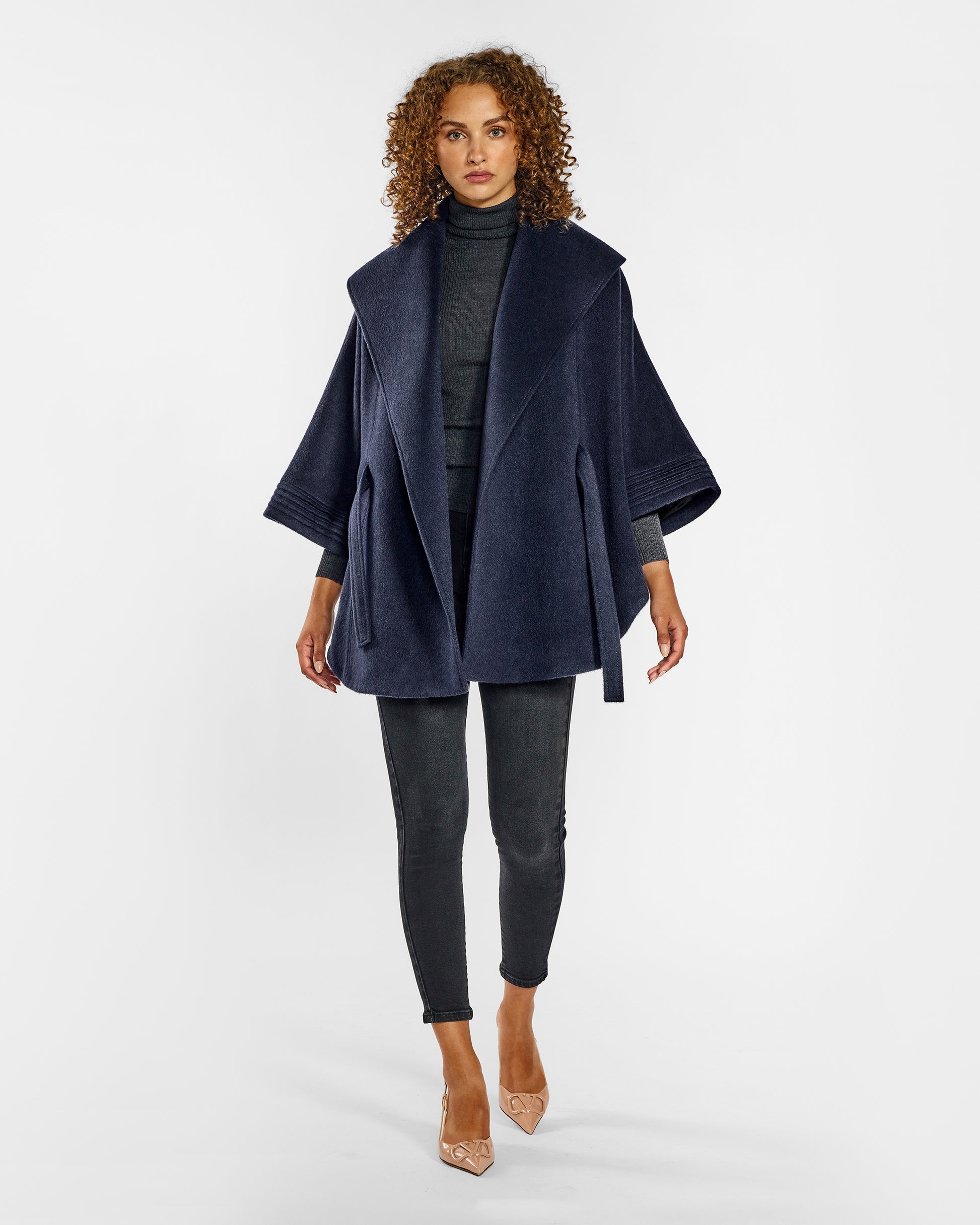 Front view of model wearing a Sentaler deep navy cape made of baby alpaca wool, with a shawl collar, worn open.