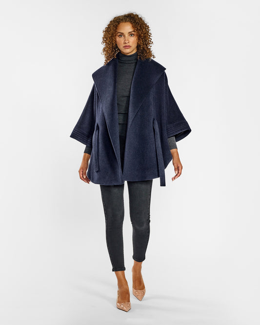 Front view of model wearing a Sentaler deep navy cape made of baby alpaca wool, with a shawl collar, worn open.