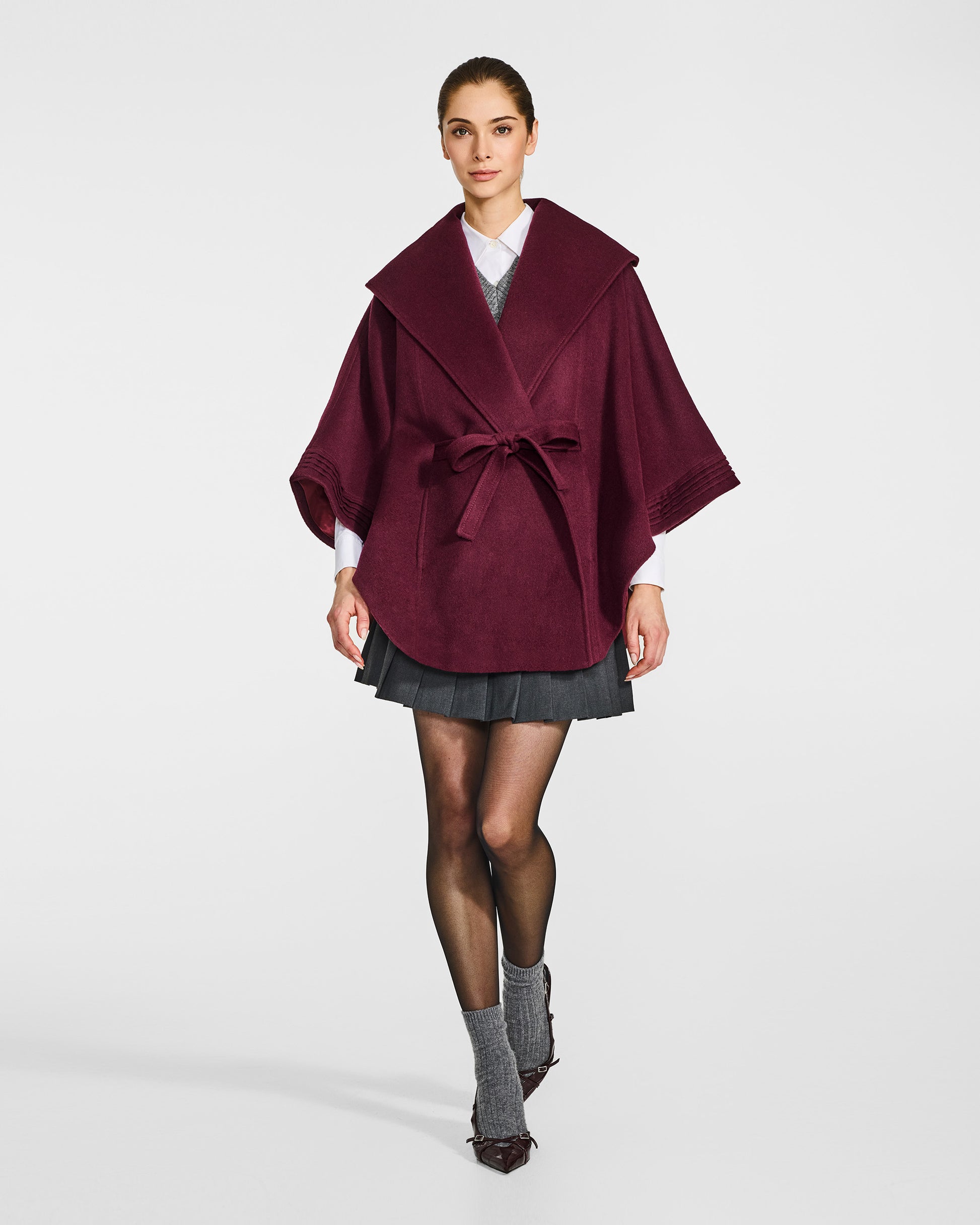 Front view of model wearing a Sentaler cherry lacquer cape made of baby alpaca wool, with a shawl collar, worn belted.