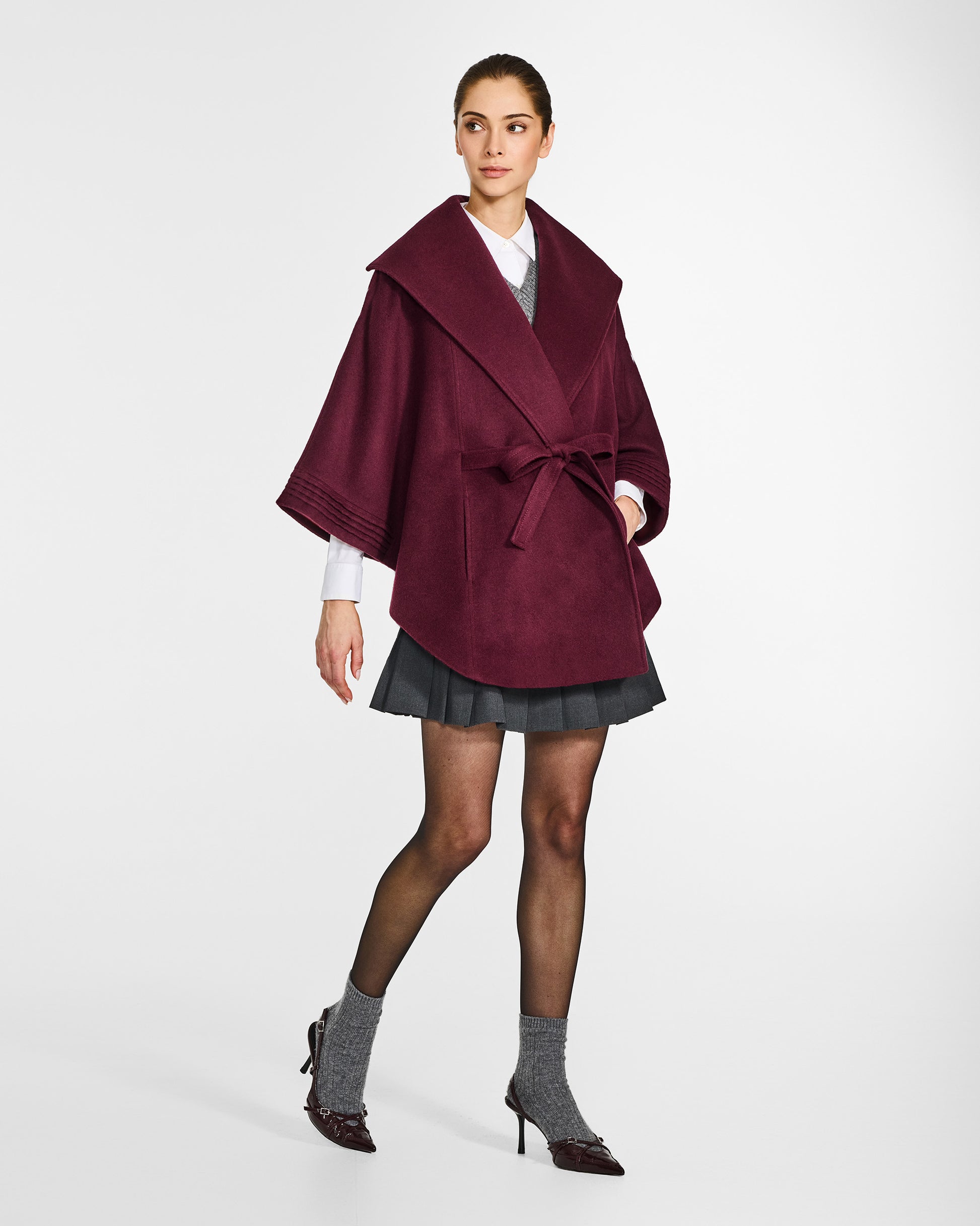 Side view of model wearing a Sentaler cherry lacquer cape made of baby alpaca wool, with a shawl collar, worn belted.