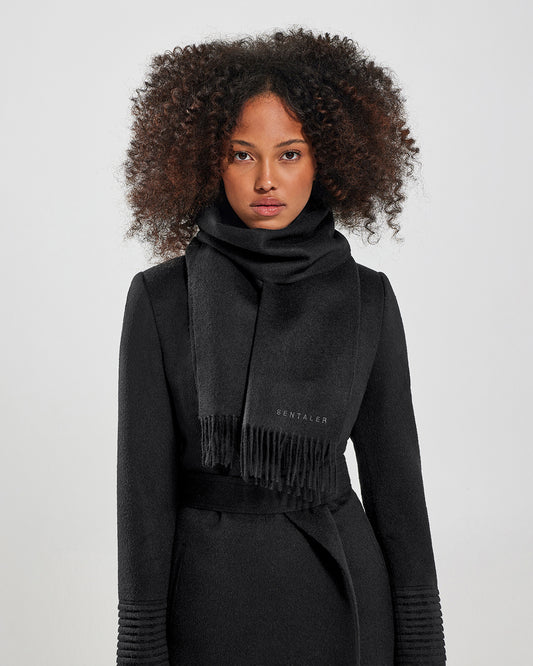 Front close up view of model wearing Sentaler's adult Black classic scarf, made of baby alpaca yarn. 