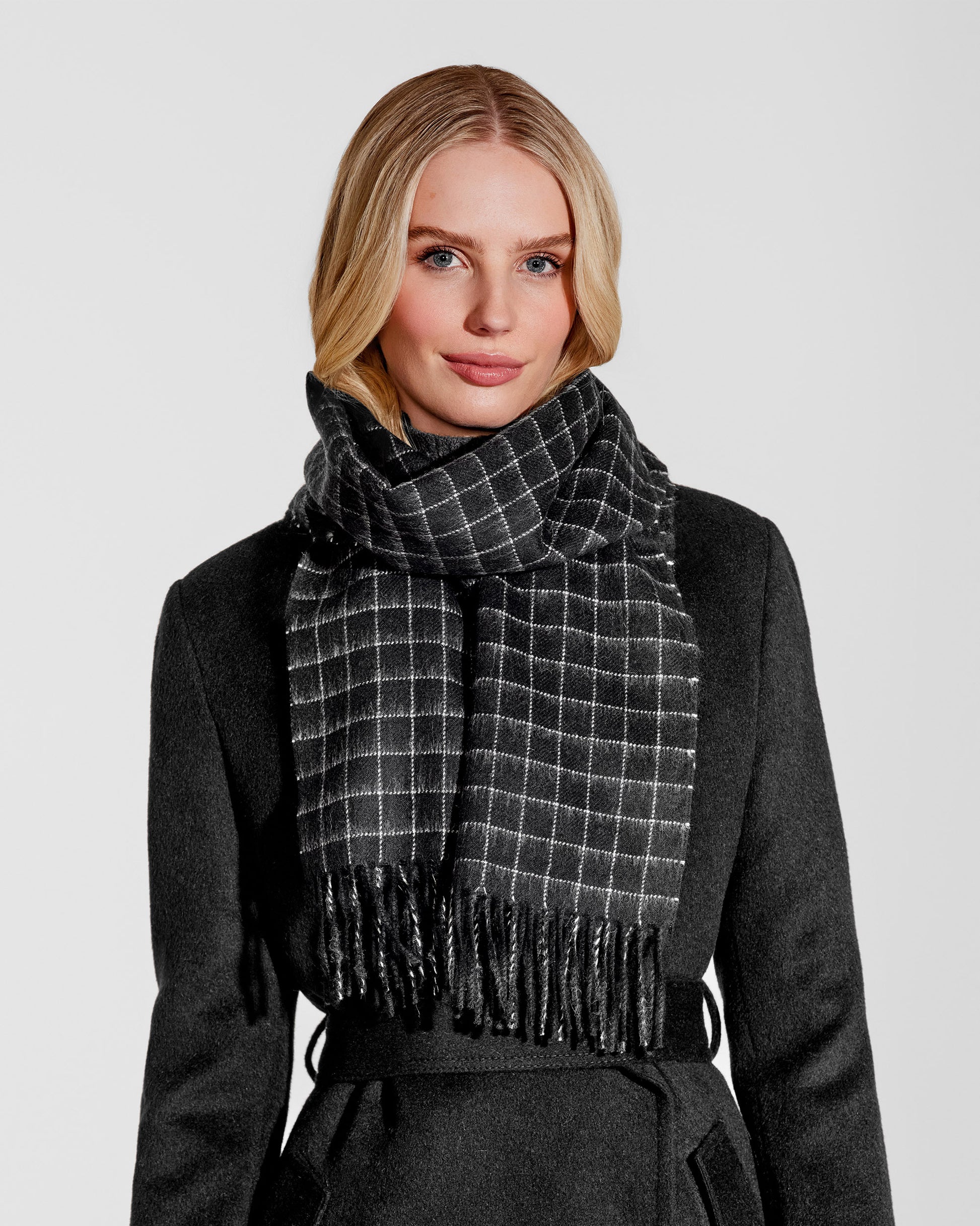 Front close up view of model wearing Sentaler's adult Black Check classic scarf, made of baby alpaca yarn. 