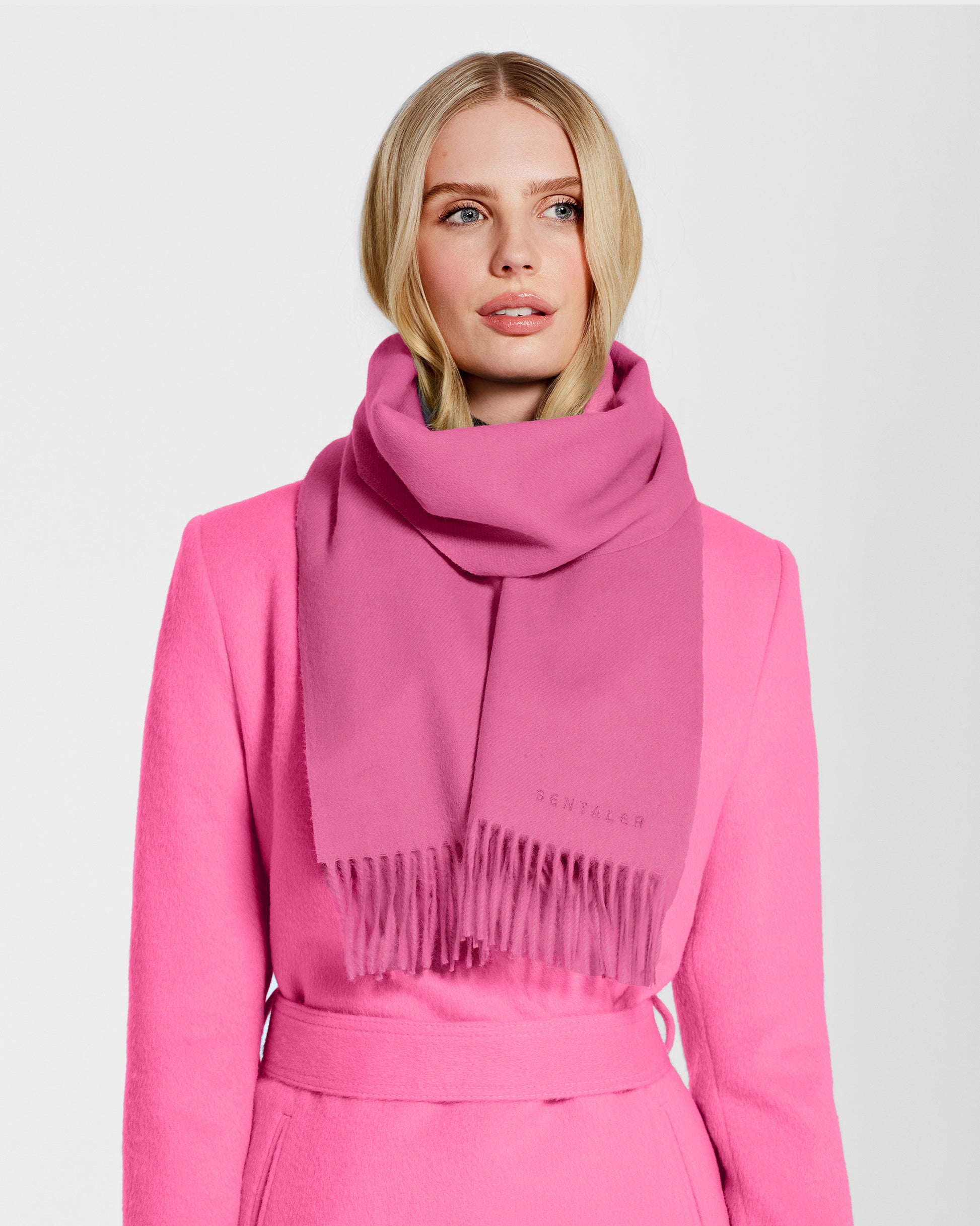 Front close up view of model wearing Sentaler's adult Cosmetic Pink classic scarf, made of baby alpaca yarn. 