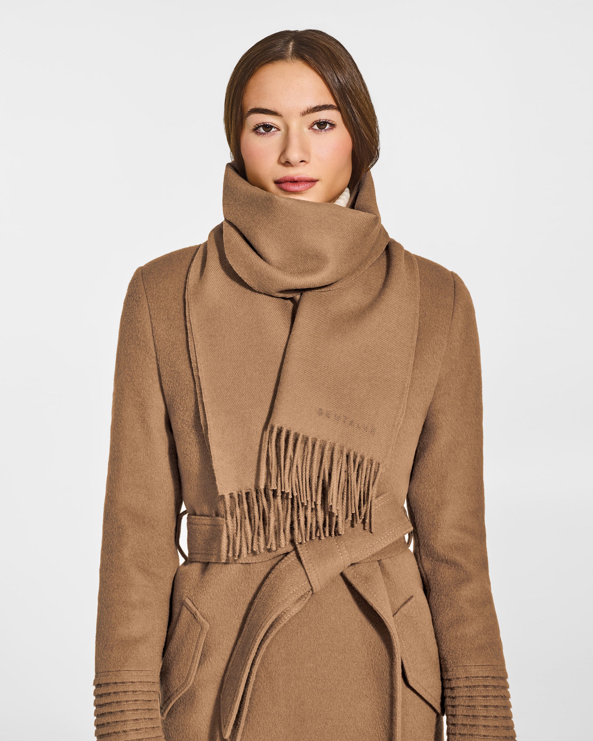 Front close-up view of model wearing Sentaler's adult Dark Camel classic scarf, made of baby alpaca yarn. 