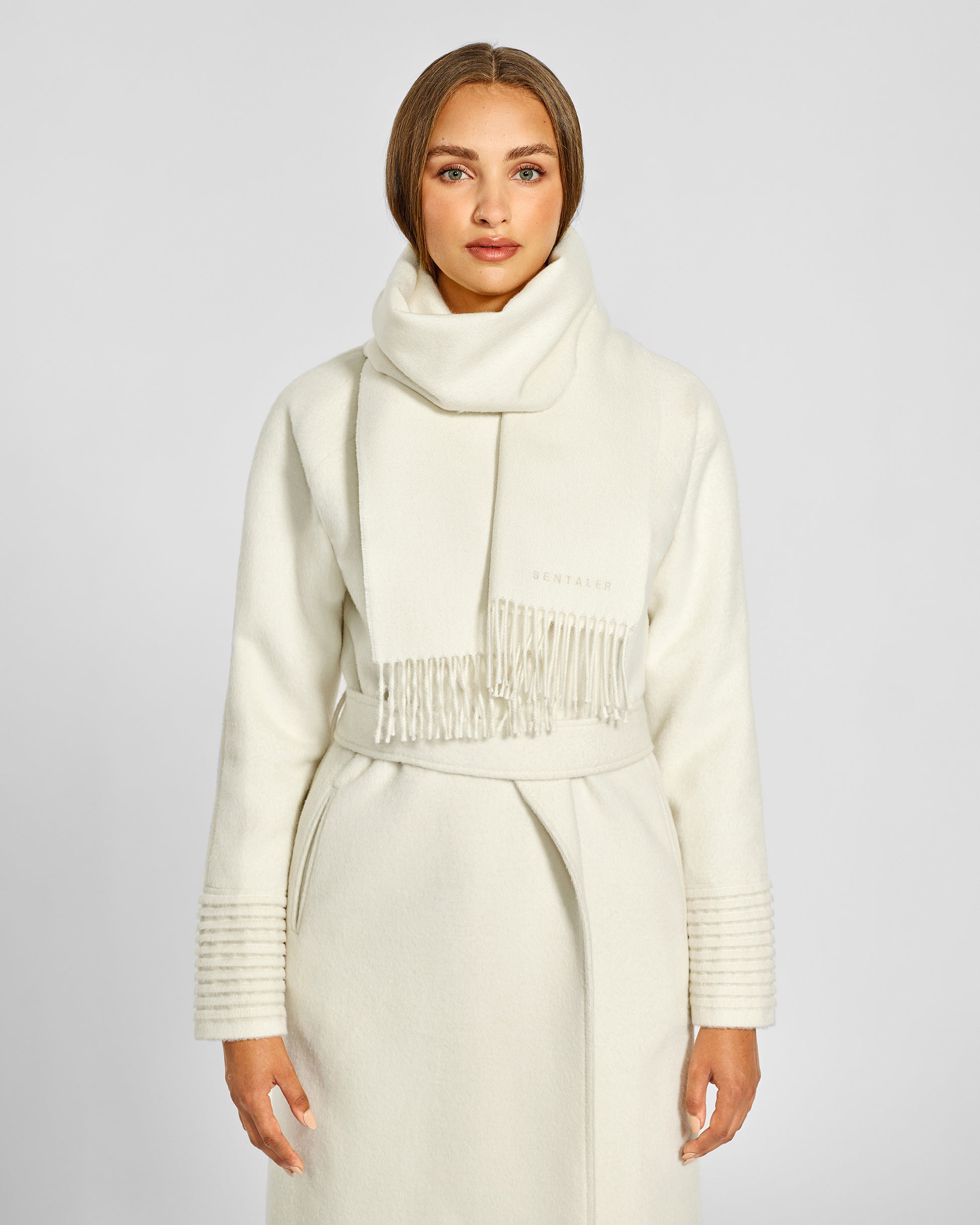 Front close up view of model wearing Sentaler's adult Ivory classic scarf, made of baby alpaca yarn. 