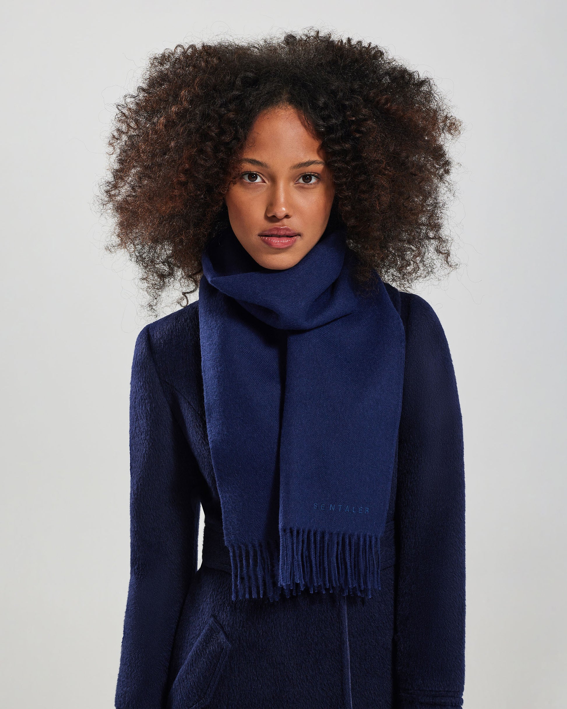 Front close up view of model wearing Sentaler's adult Navy classic scarf, made of baby alpaca yarn. 