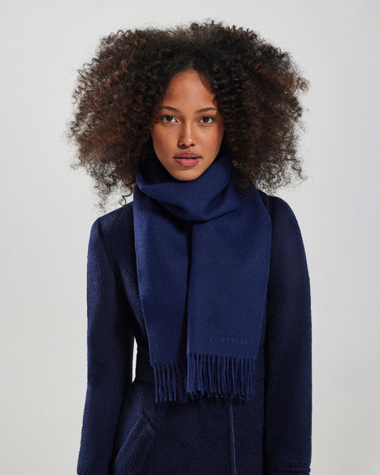 Front close up view of model wearing Sentaler's adult Navy classic scarf, made of baby alpaca yarn. 